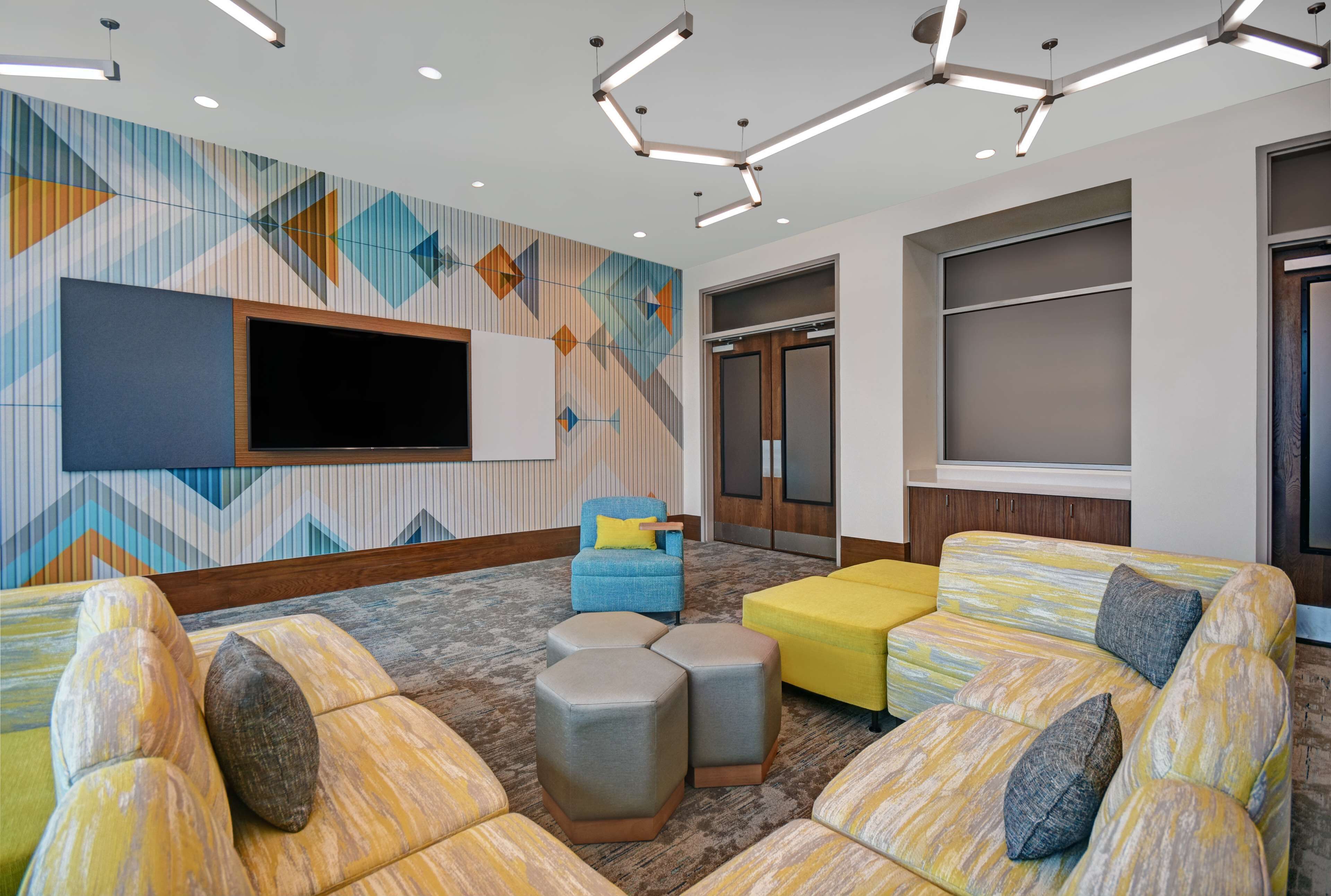 Un espace de détente moderne doté d’un grand téléviseur à écran plat, de sièges confortables et d’un mur décoratif.