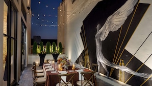 An outdoor dining area with a long table set for six, surrounded by chairs, under string lights. - 106 Jefferson Huntsville, Curio Collection by Hilton (Huntsville)