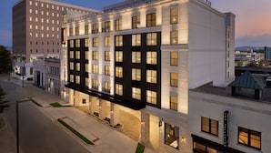 A modern hotel with a flat facade, multiple windows, and a well-lit entrance. - 106 Jefferson Huntsville, Curio Collection by Hilton (Huntsville)