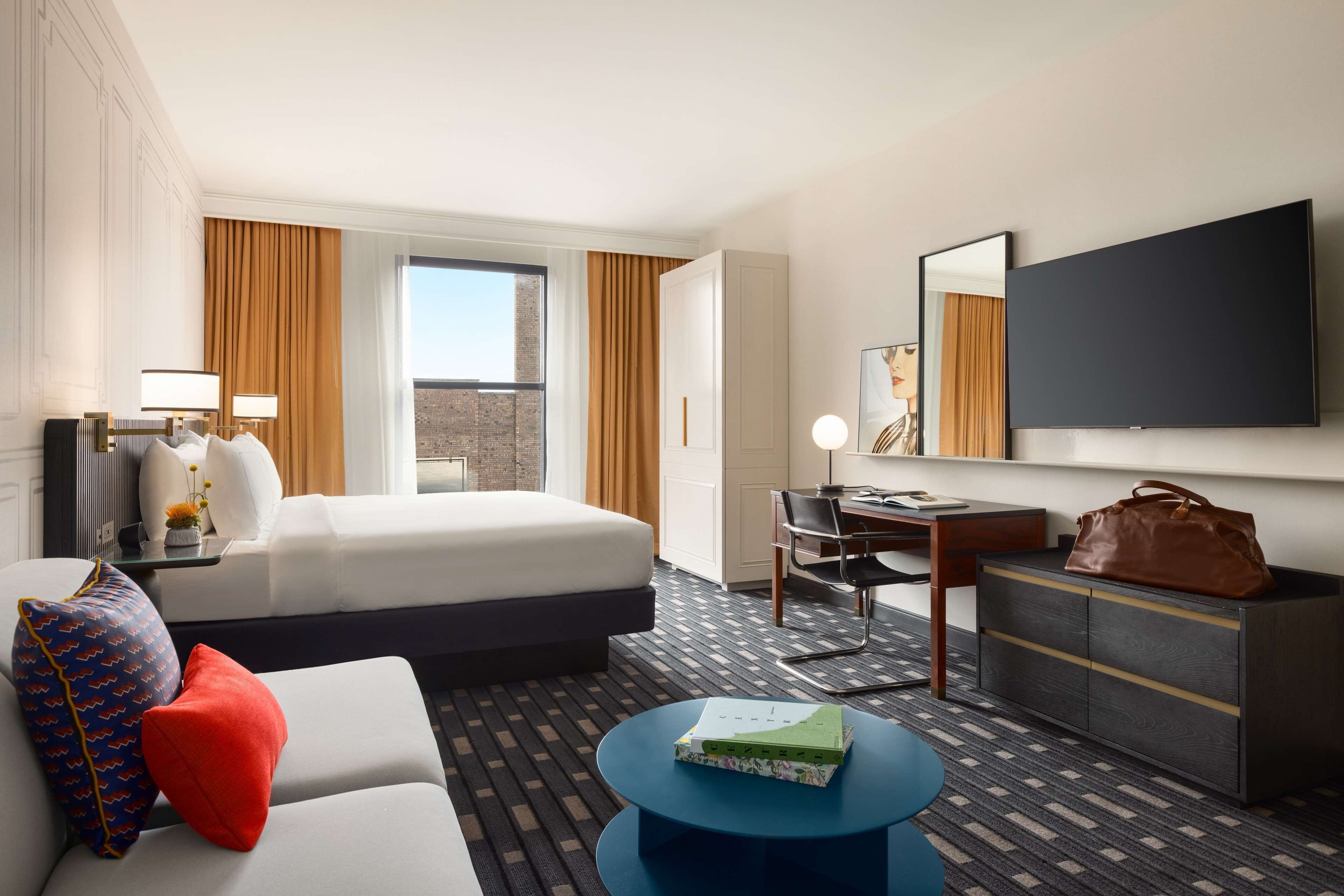 A hotel room with a bed, a desk, a chair, a TV, a sofa, and a coffee table.