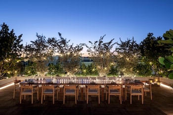 An aerial view of a modern hotel with outdoor seating areas, a long table for dining, and a well-maintained lawn. at The Ray Hotel Delray Beach, Curio Collection by Hilton