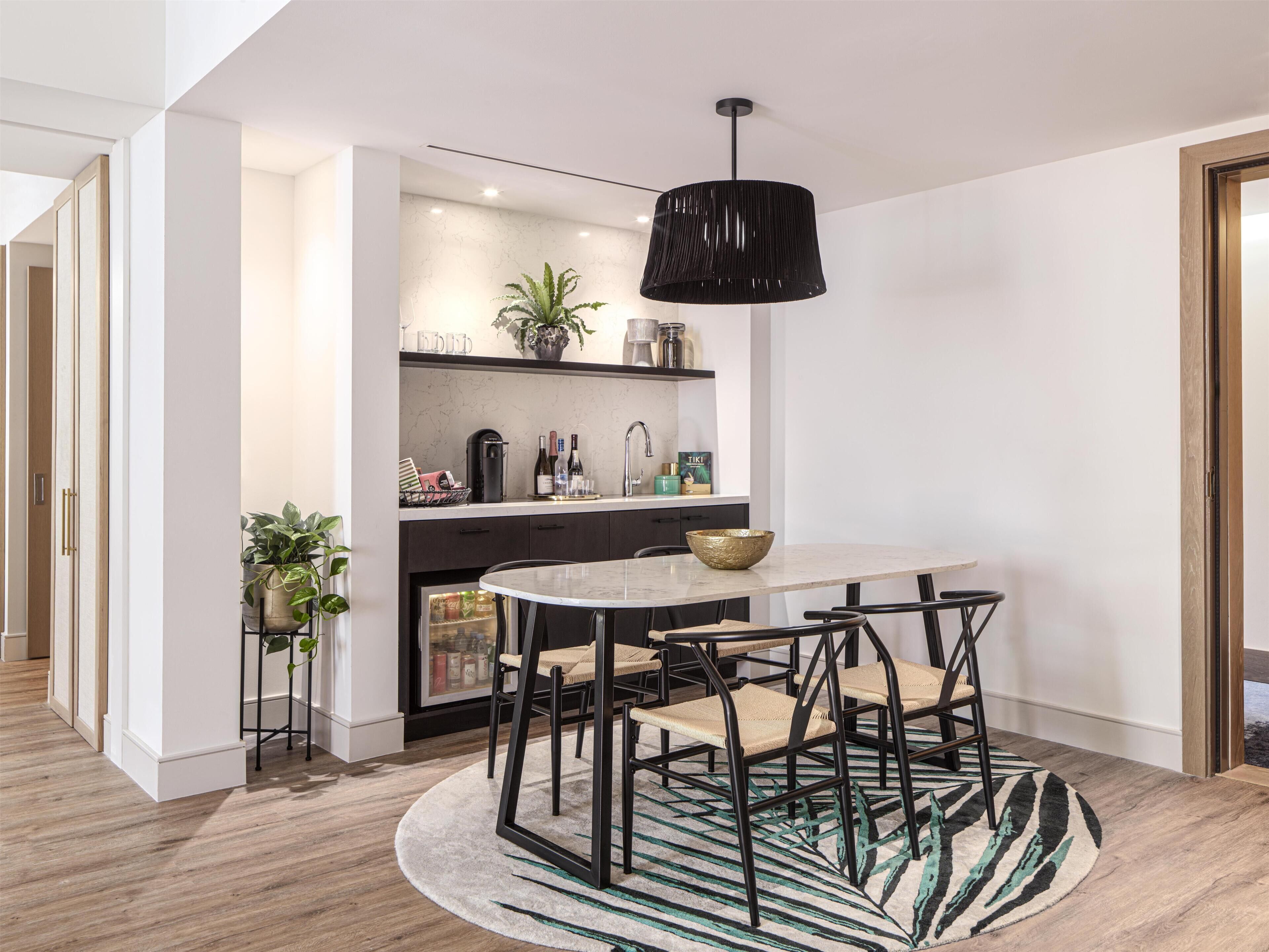 A modern kitchen with a marble countertop, black chairs, and a round table.