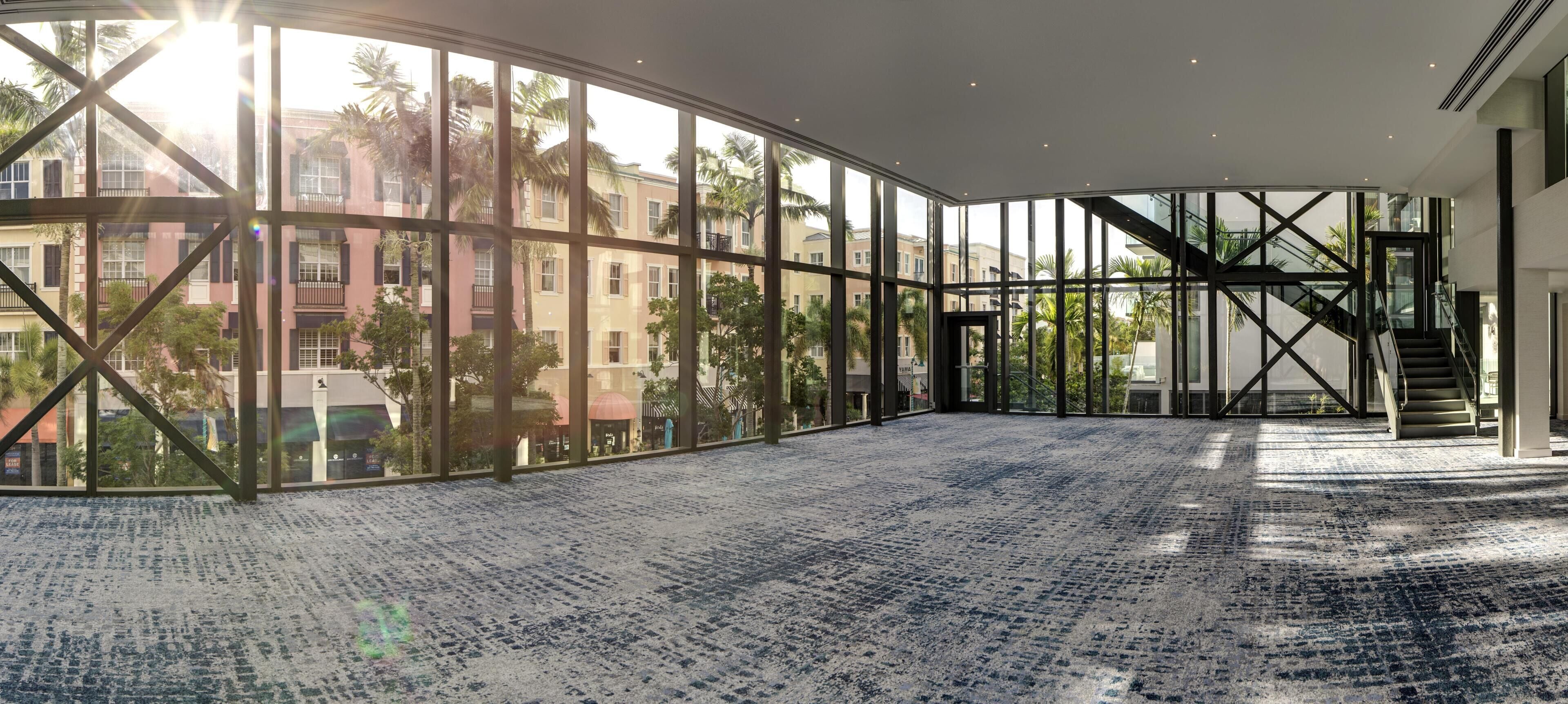 A spacious atrium with large windows, a staircase, and a patterned carpet.