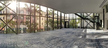 A modern hotel lobby with a seating area, a large abstract painting, and a variety of decorative items on shelves. at The Ray Hotel Delray Beach, Curio Collection by Hilton