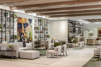 A conference room with a long table, chairs, and a large window with a view of buildings and trees. at The Ray Hotel Delray Beach, Curio Collection by Hilton