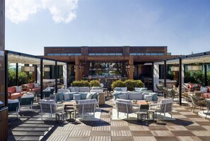 An outdoor patio with seating areas, a bar, and a view of the city. - The Ray Hotel Delray Beach, Curio Collection by Hilton (Delray Beach)
