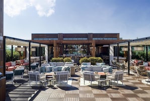 An outdoor patio with seating areas, a bar, and a view of the city.