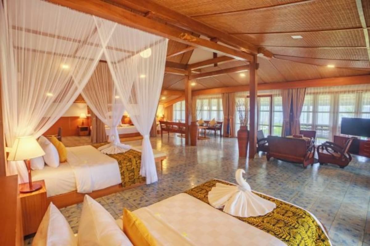A hotel room with a large bed, a smaller bed, a sitting area with a table, and a TV.