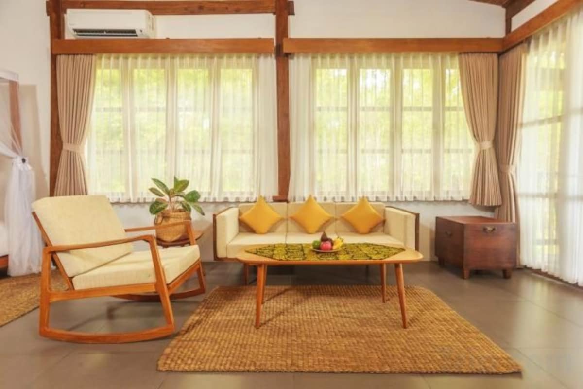 A living room with a sofa, a rocking chair, a coffee table, and a potted plant.