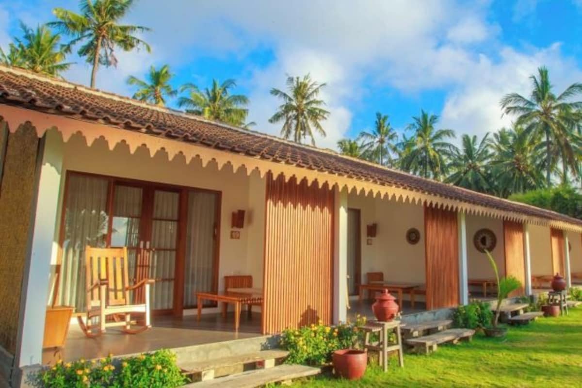 Une maison de style bungalow avec un toit en tuiles, des meubles en bois et un jardin agrémenté de plantes en pot.