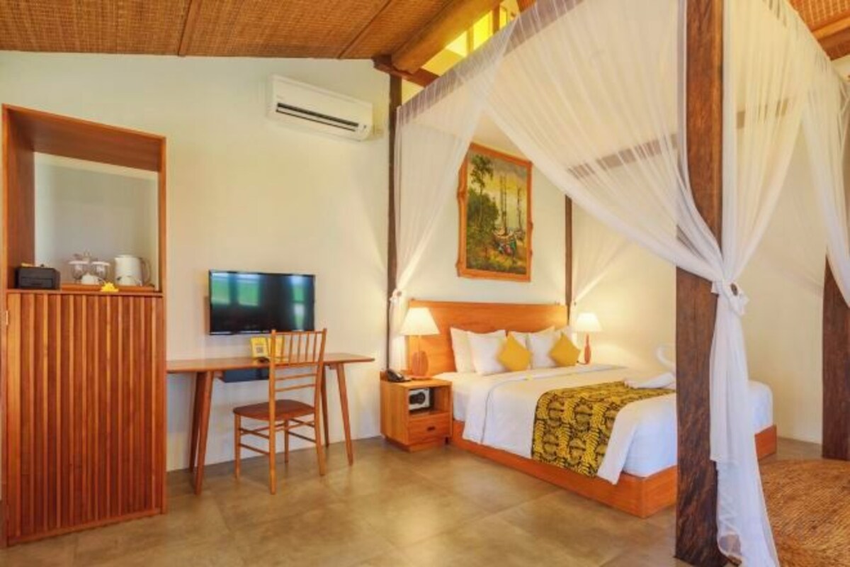 A bedroom with a bed, bedside table, lamp, and a TV.
