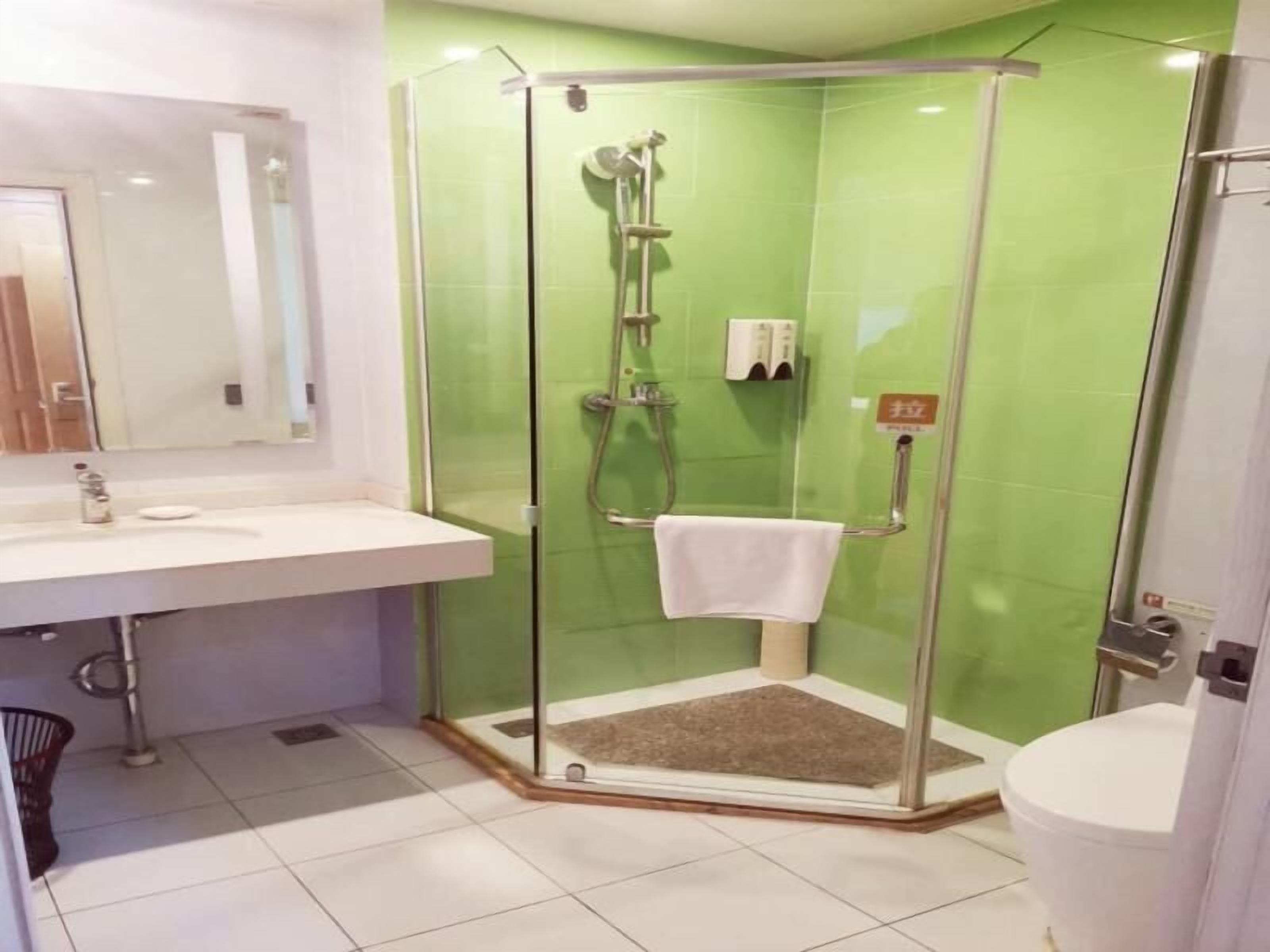 Een badkamer met een douchecabine van glas, een witte wastafel en een toilet.