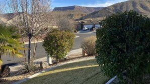 A residential area with a clear view of a parking lot, a building with a garage, and a hilly landscape in the background. - Come and Enjoy the Beauties of Southern Utah (La Verkin)