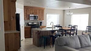 A spacious kitchen with wooden cabinets, a central island, and a dining area with a gray sofa. - Come and Enjoy the Beauties of Southern Utah (La Verkin)