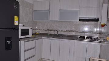 Een koelkast, een microgolfoven, kookgerei, borden en bestek