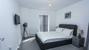 Une chambre moderne avec un grand lit, des tables de chevet, un téléviseur et un radiateur.