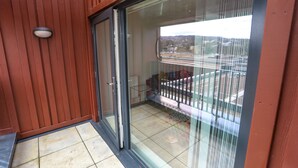 Un balcon doté d’une porte vitrée, d’une rambarde en métal et offrant une vue sur le paysage urbain.
