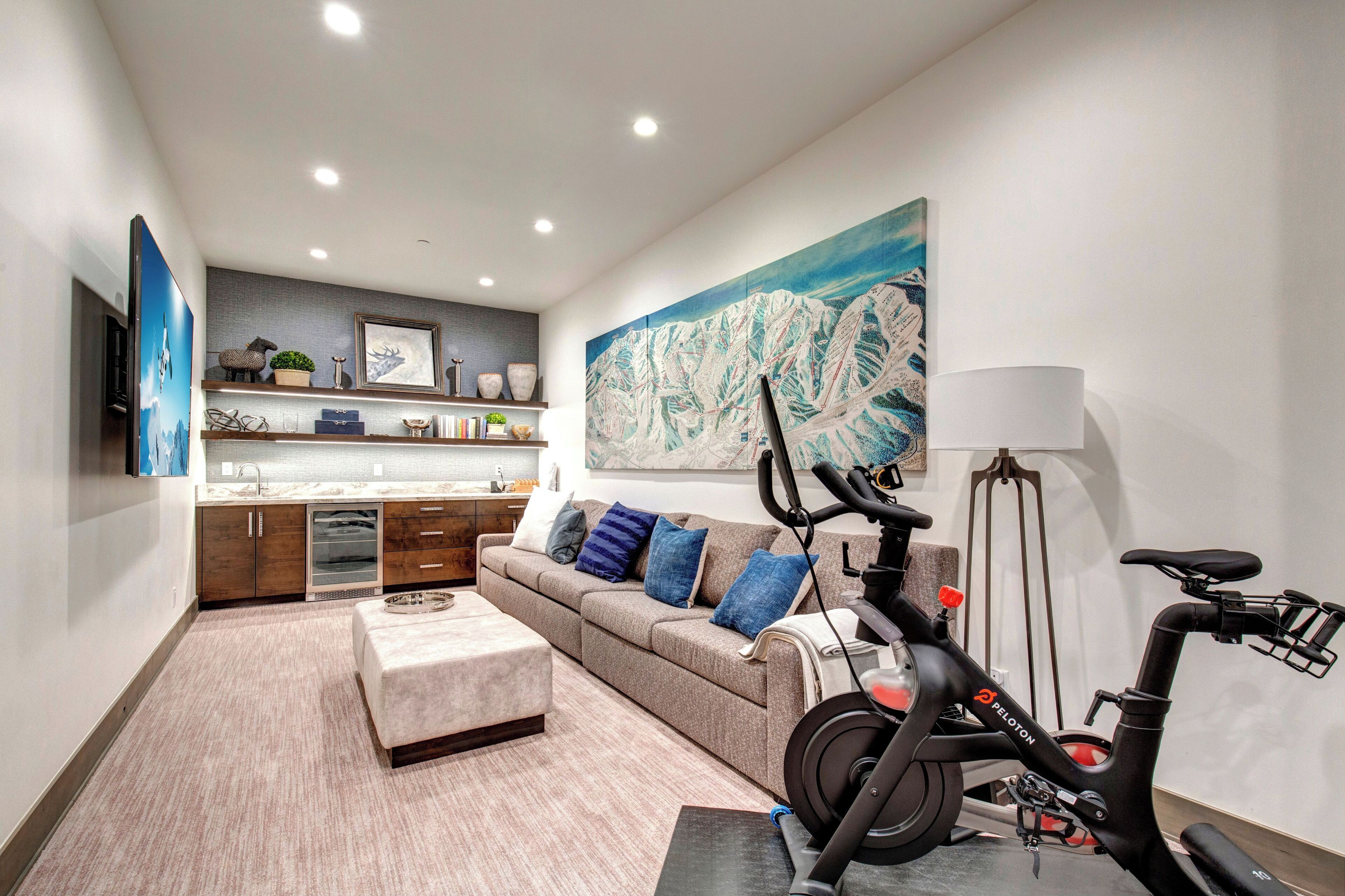 Una sala de estar moderna con sofá, reposapiés y bicicleta estática.