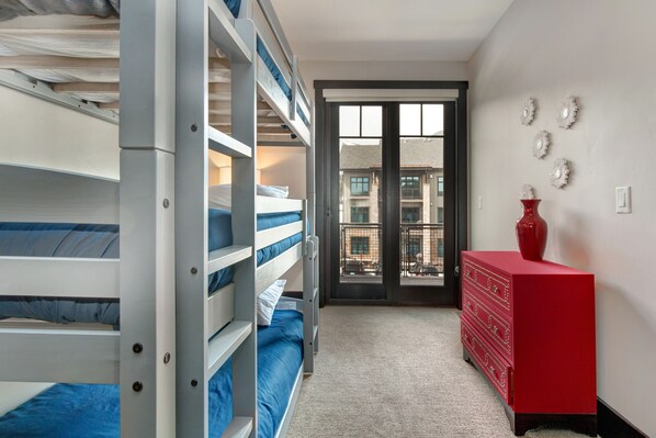 Una habitación con literas, un aparador rojo y vistas a través de un ventanal.