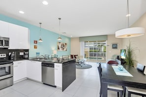 Enjoy meals in the kitchen with a central island, dishwasher, and microwave, adjacent to a dining area with a table and chairs.