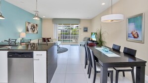 A modern kitchen with a dishwasher, dining area with a table and chairs, and a large window with a view of greenery. - EV_1445 – 3 Bed, 3 Bath with Private Pool and Access to Amazing Resort Amenities (clermont)