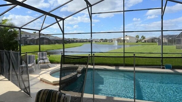 A pool area with a view of a golf course, enclosed by a metal structure. - Ref 410 .Stunning villa with own pool. Lake view Near Disney (Kissimmee)