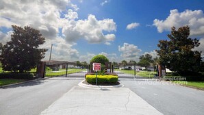 A gated entrance with a STOP sign, surrounded by well-maintained landscaping and trees. - Ref 410 .Stunning villa with own pool. Lake view Near Disney (Kissimmee)