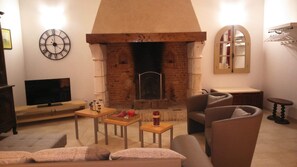 Cozy living room with a brick fireplace, flat-screen TV, and comfortable sofa.