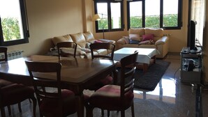 A living room with a sofa, chairs, a dining table, and a TV.