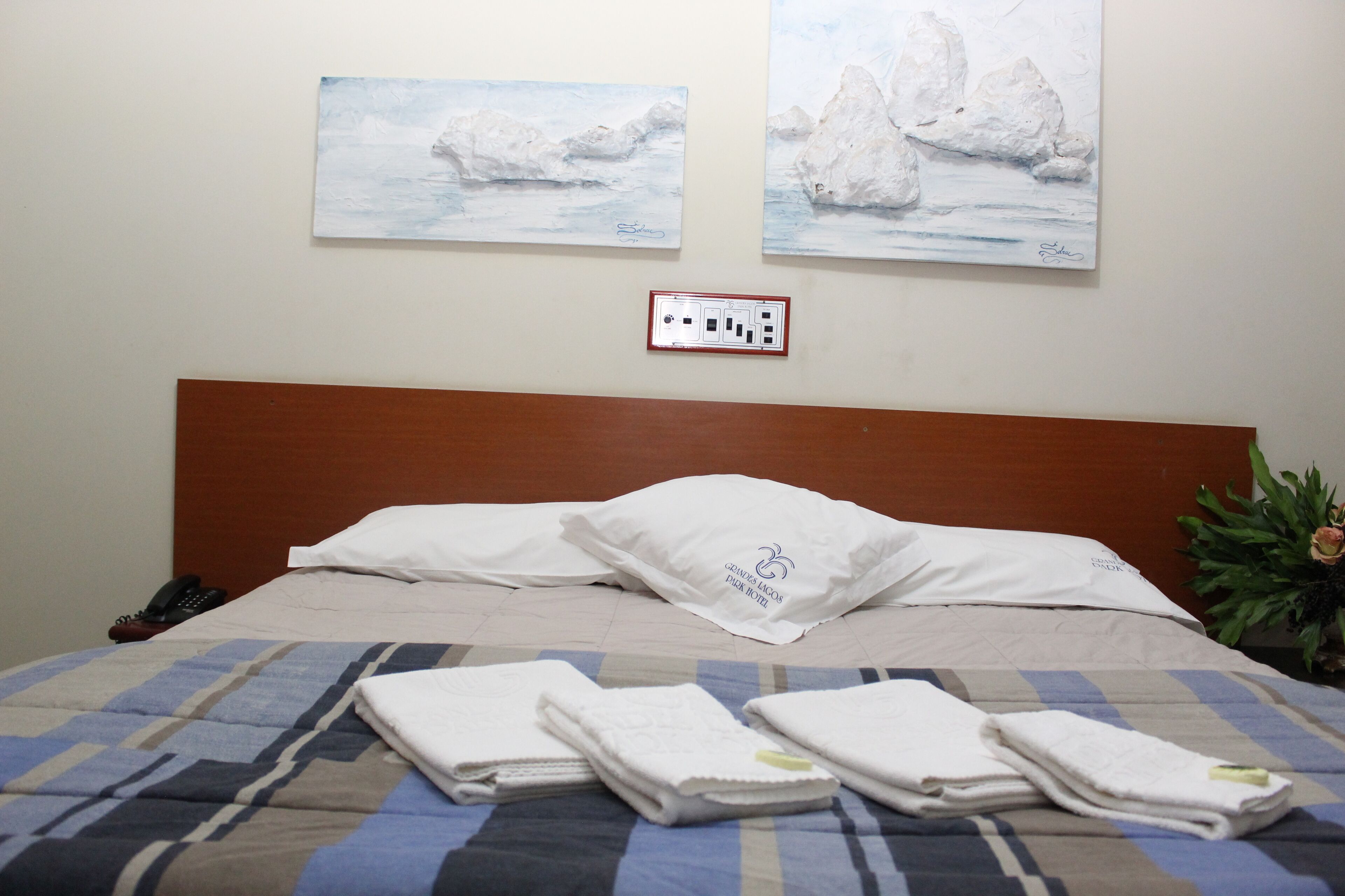 A hotel room with a bed, two paintings of polar bears, a power outlet, and a plant.