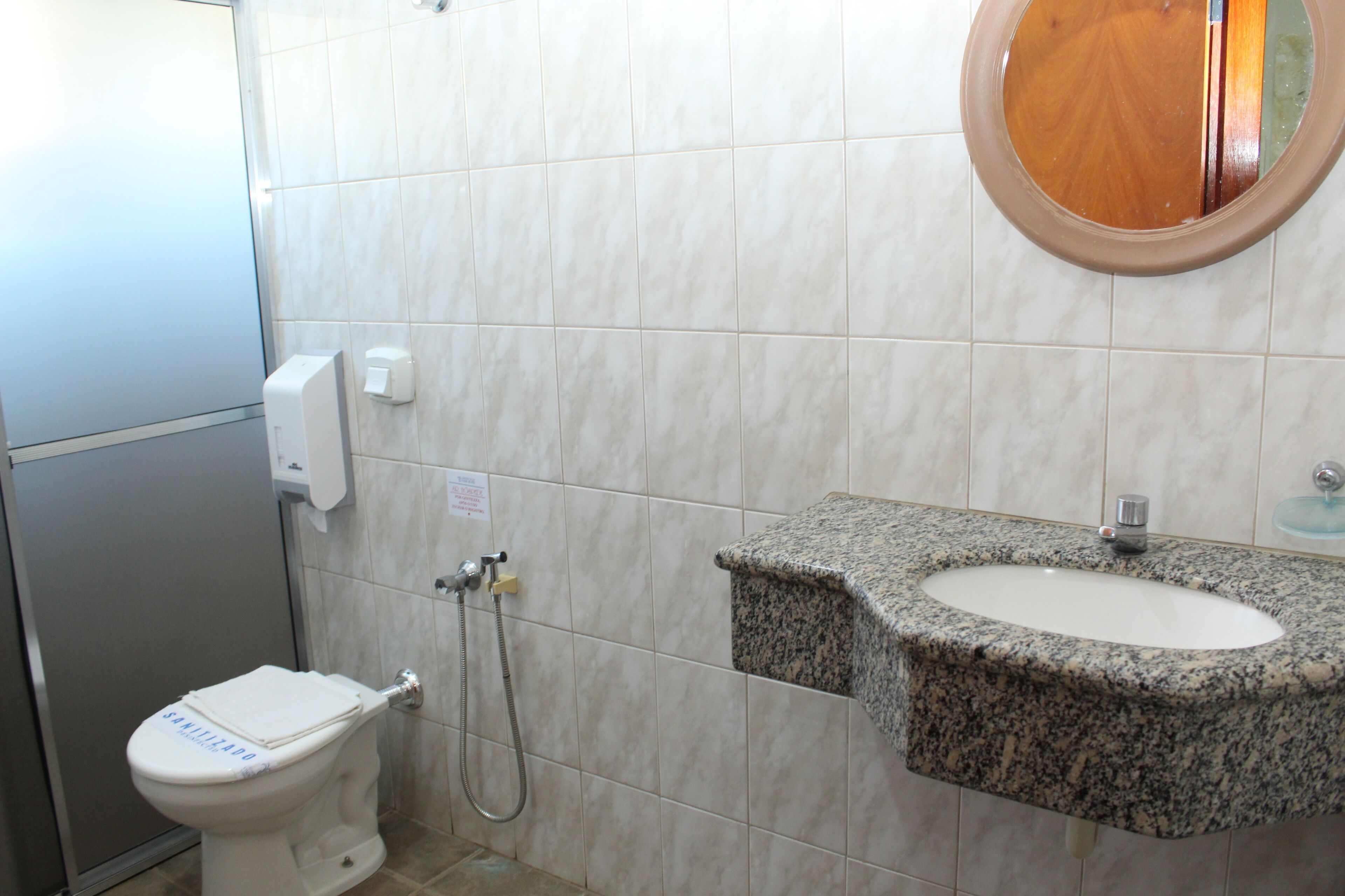 A bathroom with a toilet, a sink, and a mirror.