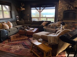 Relax by the fireplace in this inviting living room with a piano and scenic views.