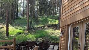 A patio area with stone flooring, outdoor seating, and a wooden deck.