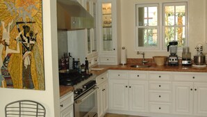 A kitchen with white cabinets, a stove, and a window with a view of greenery. - Spectacular Townhome Close to Beach (Los Angeles)