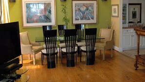 A dining area with a glass table surrounded by chairs, a television, and framed artwork on the walls. - Spectacular Townhome Close to Beach (Los Angeles)