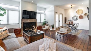 A spacious living room with a fireplace, comfortable seating, a dining area, and a TV. - Your Trendy San Diego Home, 2-Bedroom with Private 2-Car Garage (San Diego)