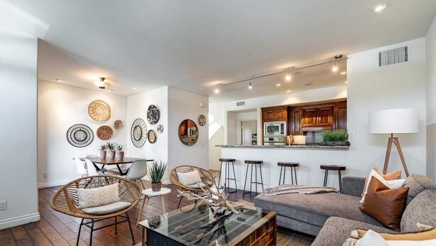 A modern living room with a glass coffee table, wicker chairs, and a grey sofa. - Your Trendy San Diego Home, 2-Bedroom with Private 2-Car Garage (San Diego)