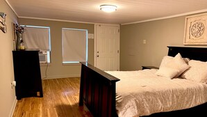 A bedroom with a bed, a dresser, a window, and a door. - False River Waterfront property (Jarreau)