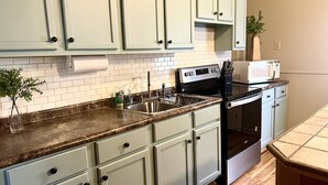 A kitchen with light blue cabinets, a stainless steel sink, a microwave, and a stove. - False River Waterfront property (Jarreau)