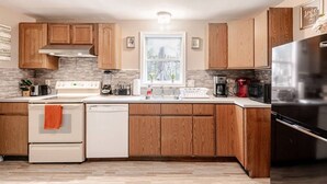 A modern kitchen with wooden cabinets, a stainless steel refrigerator, and a window with a view.