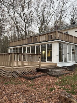 A house with a covered porch, a fenced yard, and a wooded background.