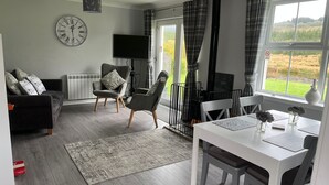 A modern living room with a sofa, chairs, a dining table, and a TV. - Blinkbonnie Cottage, a place of tranquillity & beauty in a country setting. (Wester Lix)