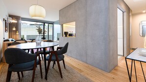 A modern dining area with a round table, dark chairs, and a wooden floor.