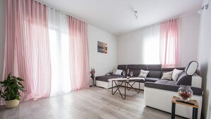 A modern living room with a grey sofa, a coffee table, and a small side table with a vase. - Holiday Home J&D No.3-Six Bedroom House  with Pool (Podstrana)