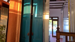 A wooden staircase with a handrail, leading to a room with teal doors and a view of the outside. - Asante Sana Beach Cottages - Deluxe Beachfront Cottage  (Fukuchani)