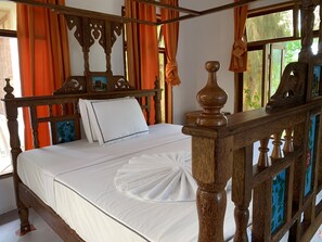 Ein hölzernes Himmelbett mit weißen Leinentüchern und einem Zierhandtuch.