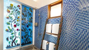 A bathroom with blue mosaic tiles, a wooden ladder with towels, and a floral mural on the wall. - Asante Sana Beach Cottages - Deluxe Beachfront Cottage  (Fukuchani)