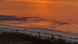 Atardecer sobre un mar tranquilo con una playa arenosa al frente.
