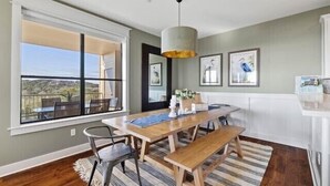 Un comedor con un ventanal grande, una mesa de madera, bancos y una lámpara colgante.