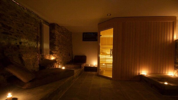 Une salle de spa avec des murs en pierre, des bancs en bois et un sauna en bois.